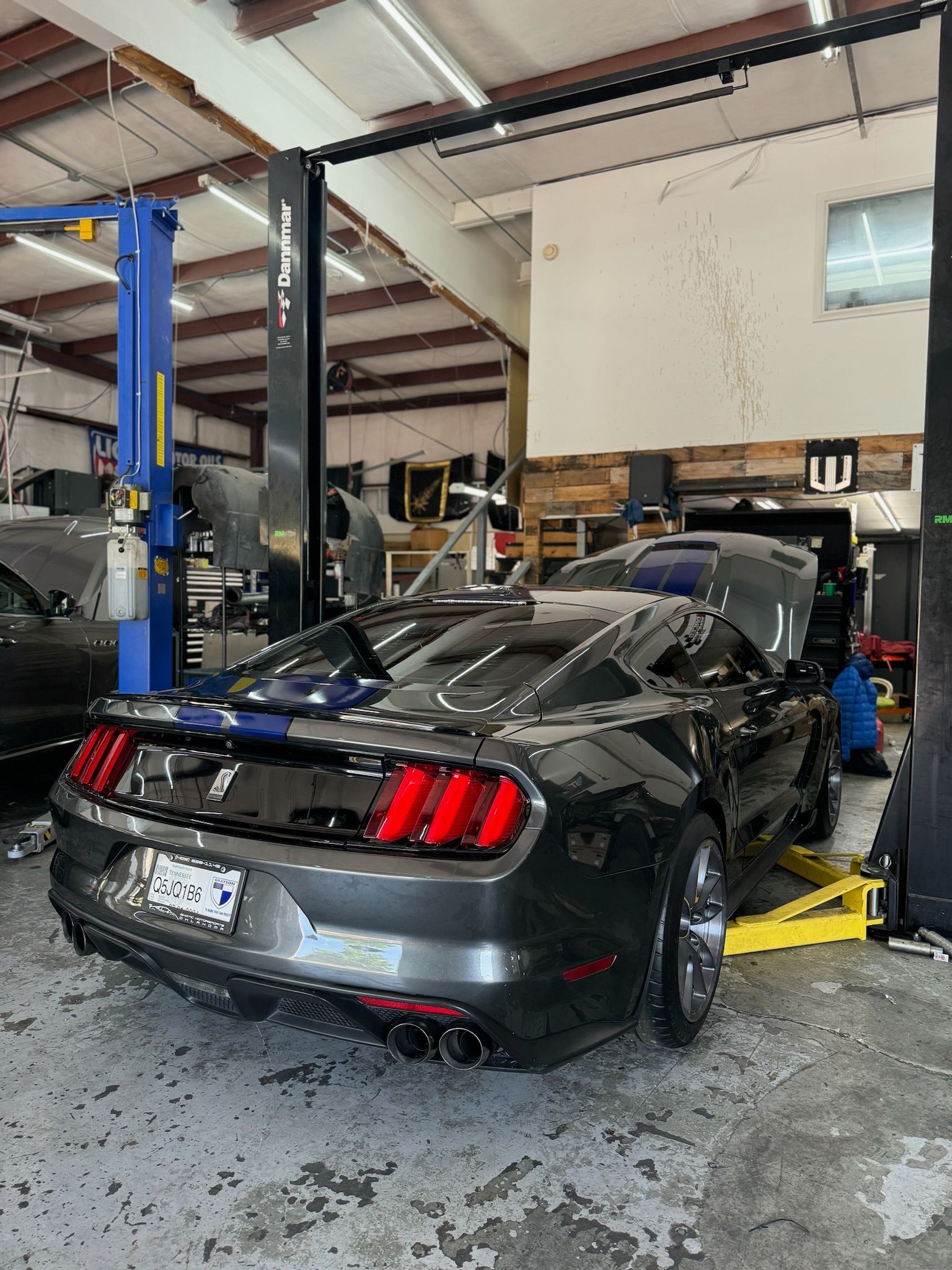 A ford mustang is sitting on a lift in a garage.