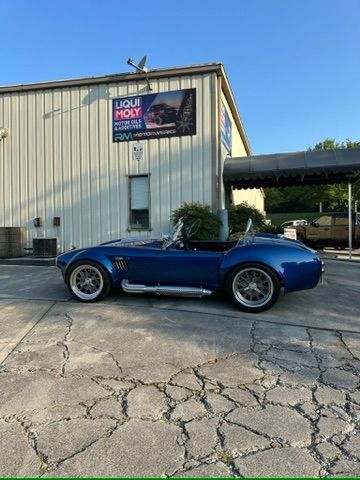 A blue sports car is parked in front of a building.