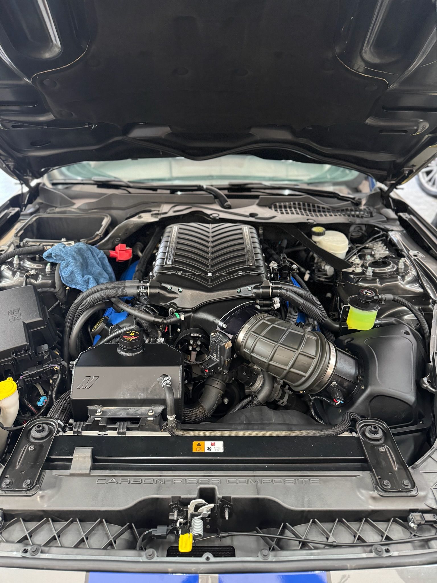 The engine of a ford mustang is shown with the hood open.