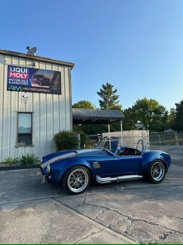 A blue sports car is parked in front of a liqui moly building.