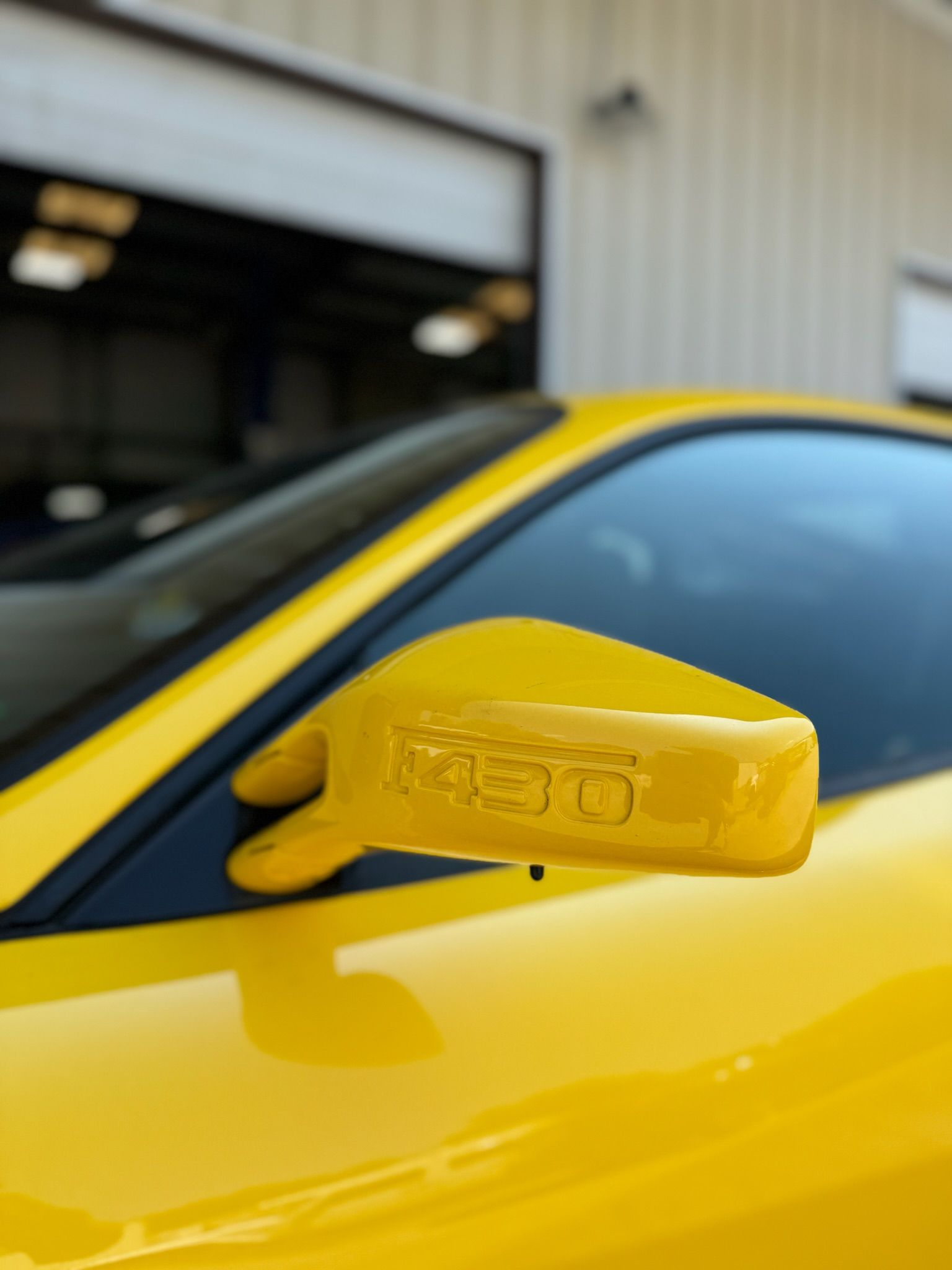 A close up of a yellow car 's side mirror
