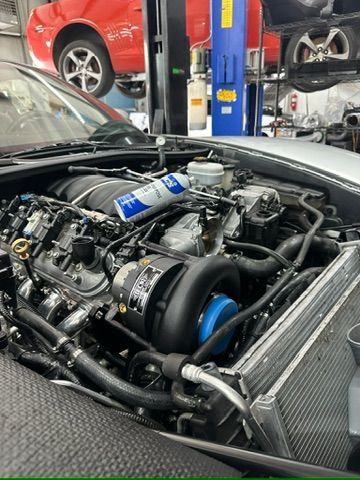 A close up of a car engine with the hood open