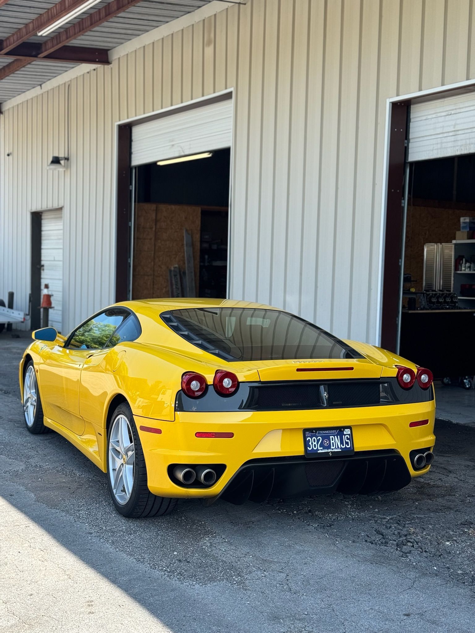 A yellow ferrari is parked in front of a garage.