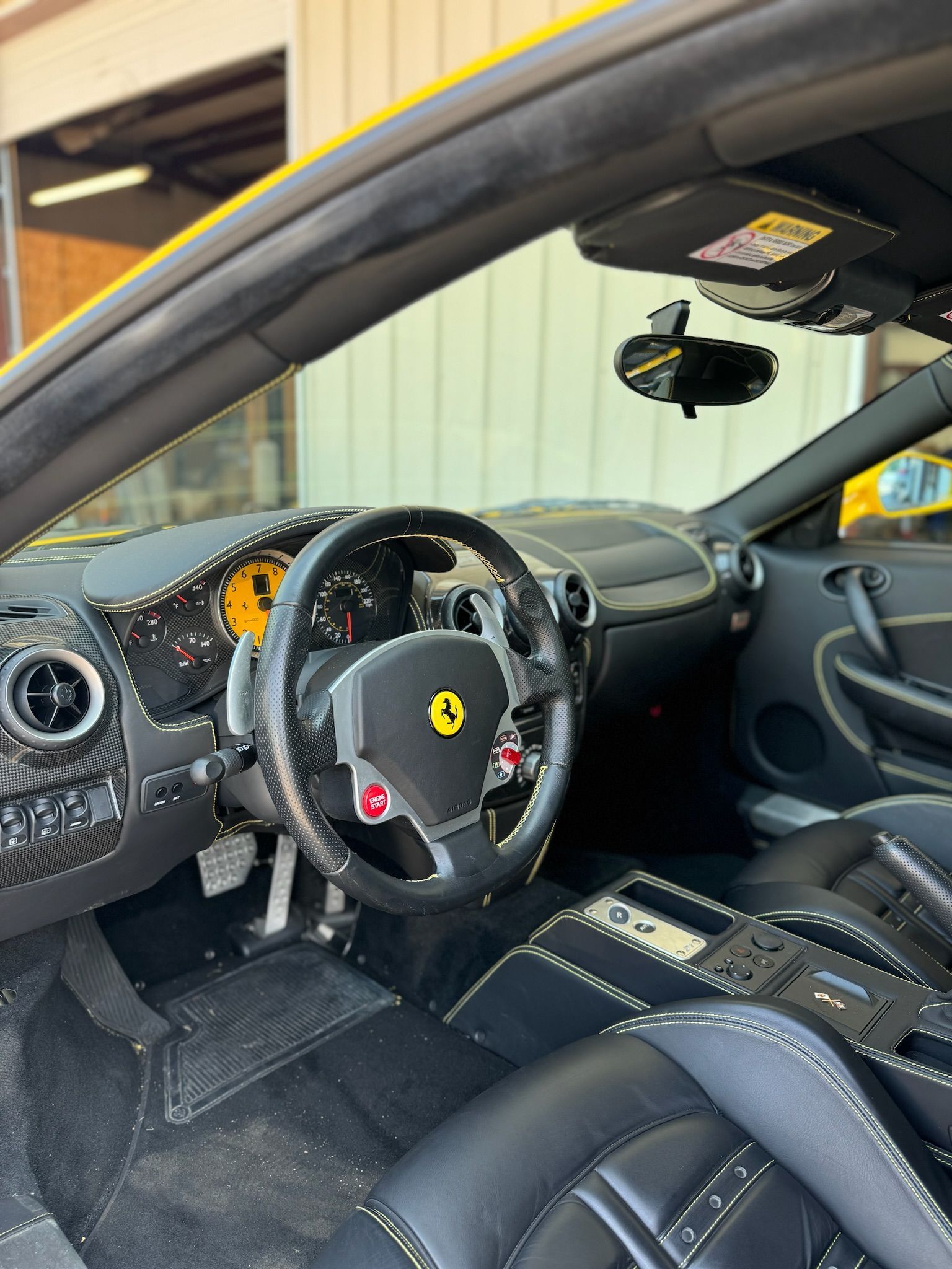 The interior of a yellow ferrari sports car is shown.