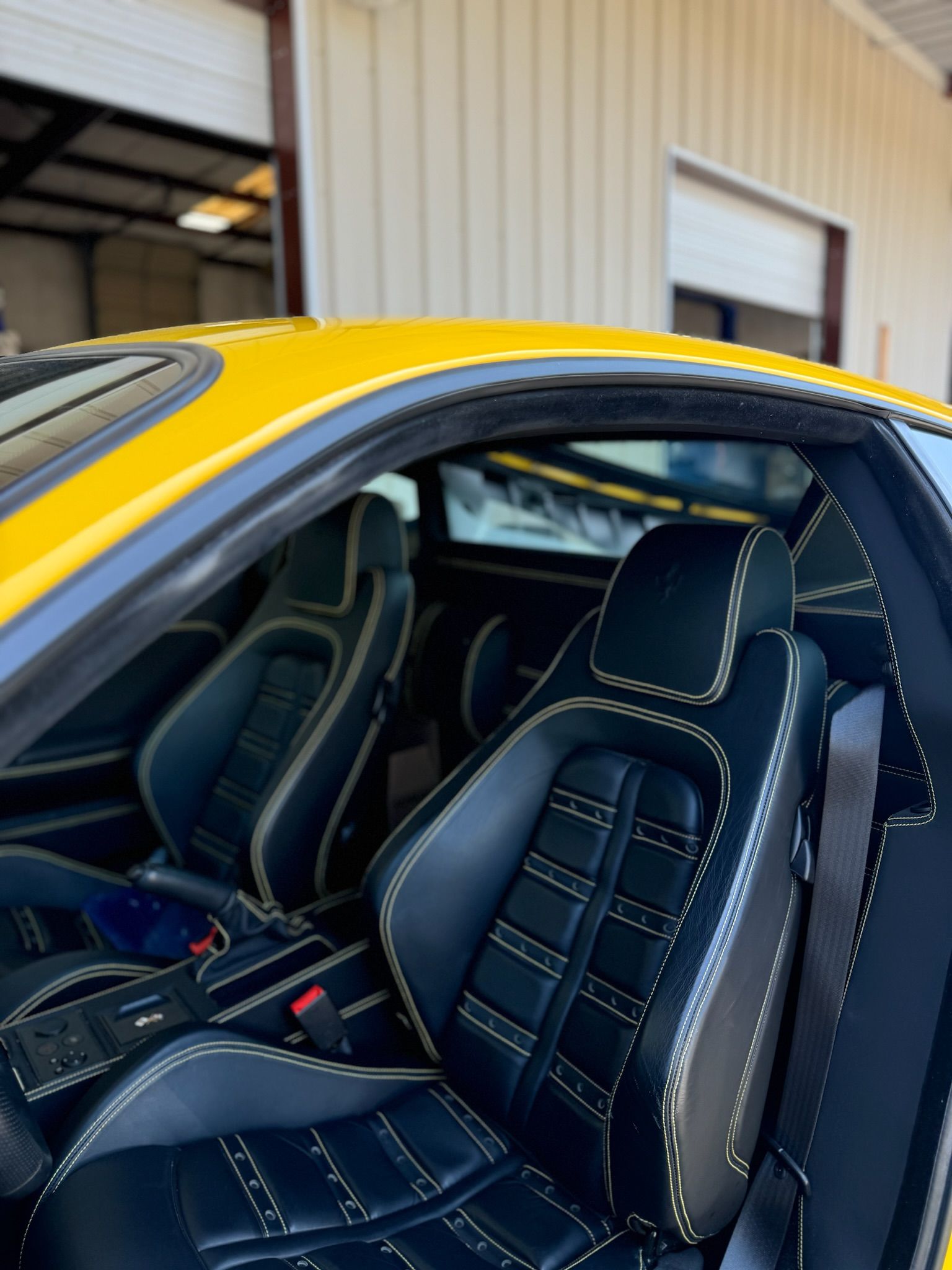 The inside of a yellow sports car with black seats