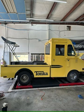 A yellow tonka truck is parked in a garage