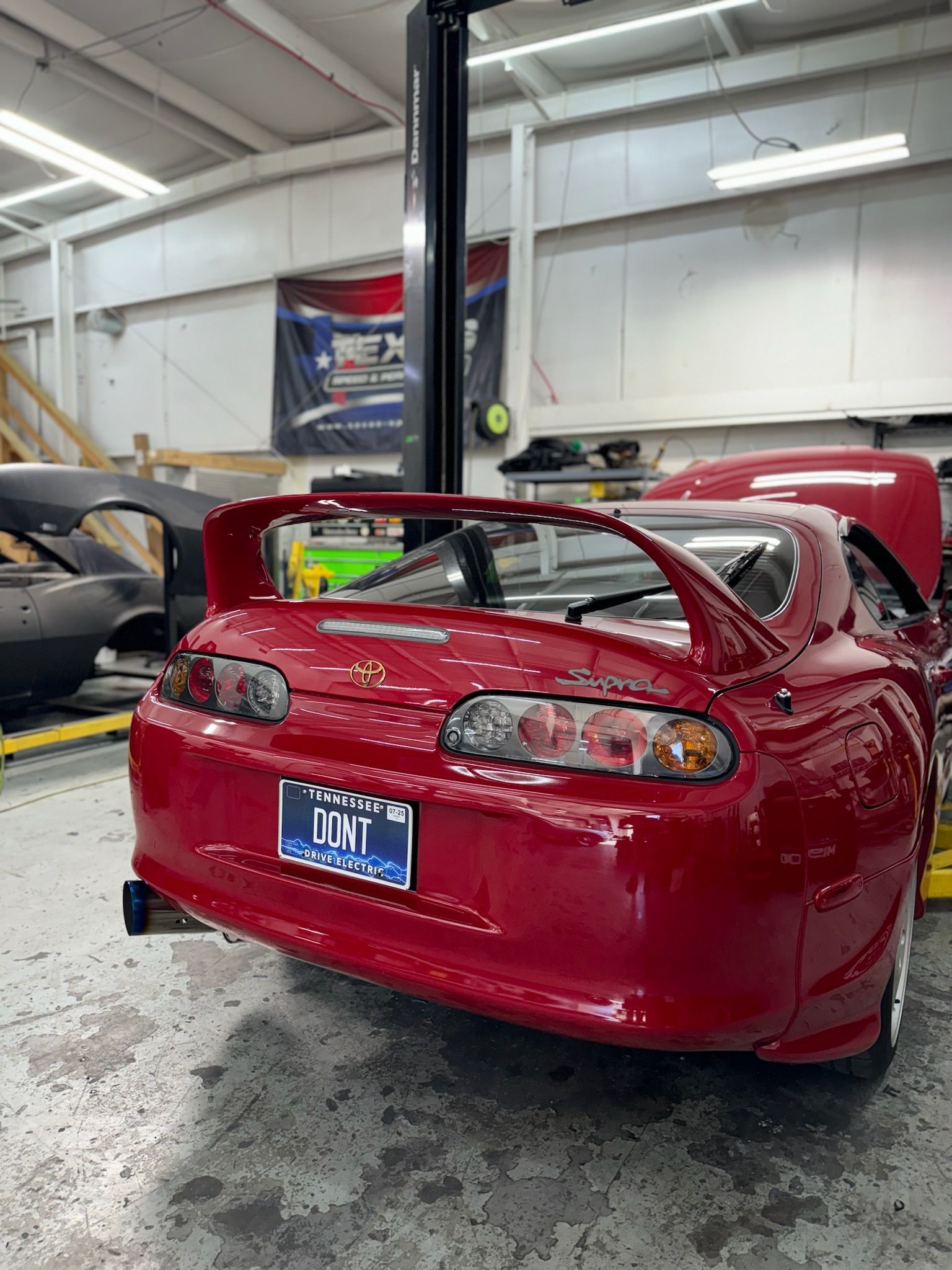 A red car with a license plate that says dmt is parked in a garage.