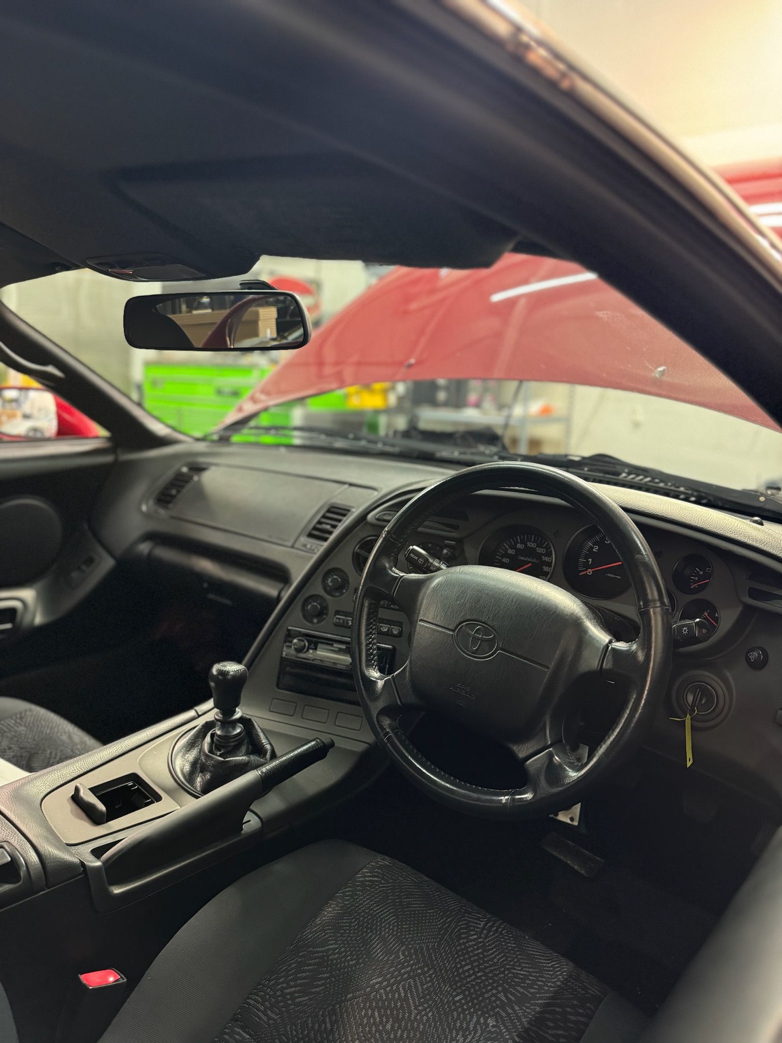 The inside of a car with a steering wheel and a rear view mirror