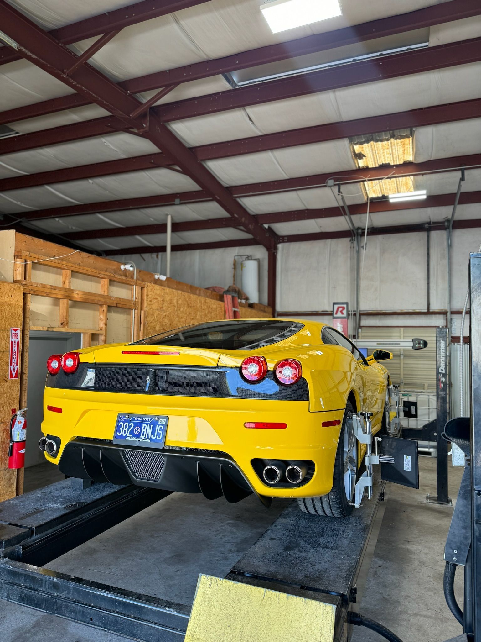 A yellow sports car is sitting on a lift in a garage.