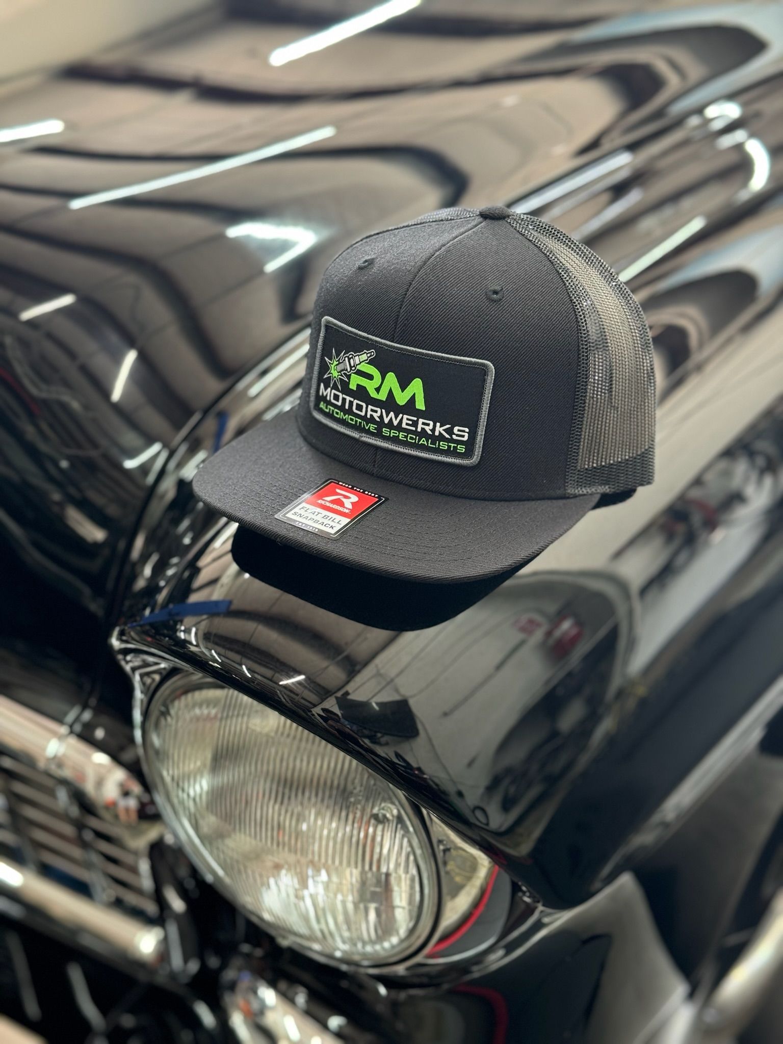 A black hat is sitting on the hood of a black car.