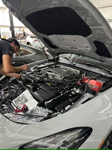 A man is working on the engine of a car with the hood open.