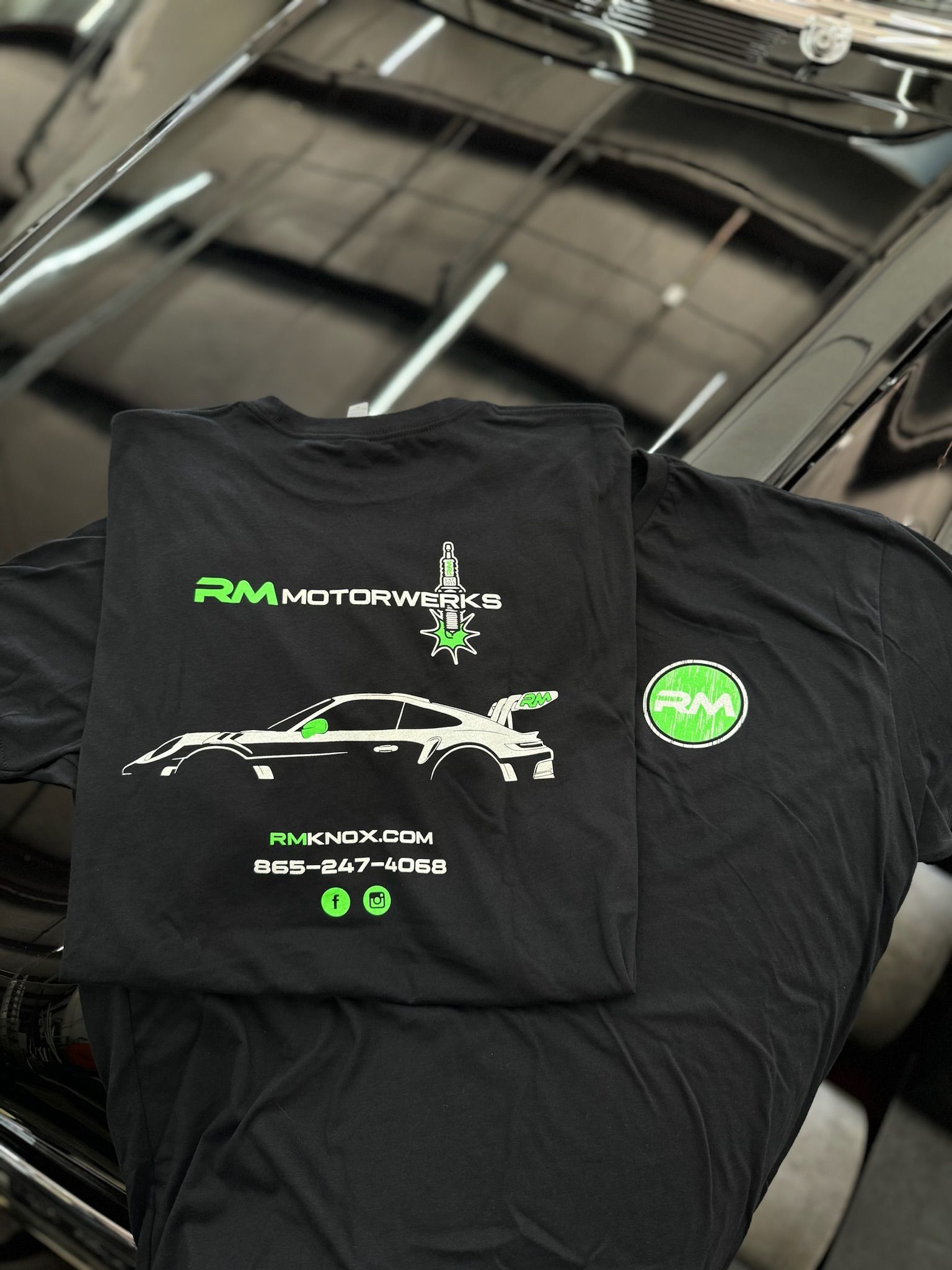 A black t-shirt is sitting on top of a black car.