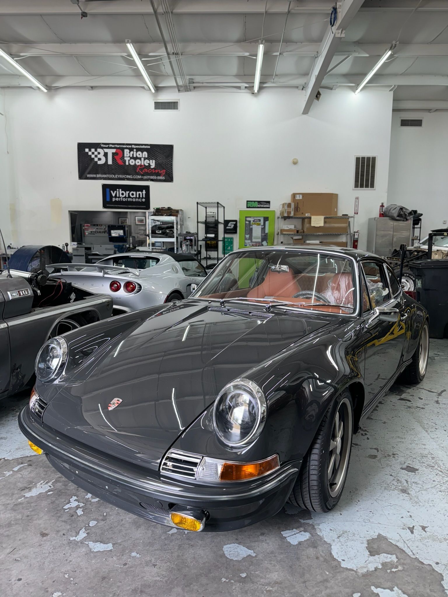 A gray porsche 911 is parked in a garage.