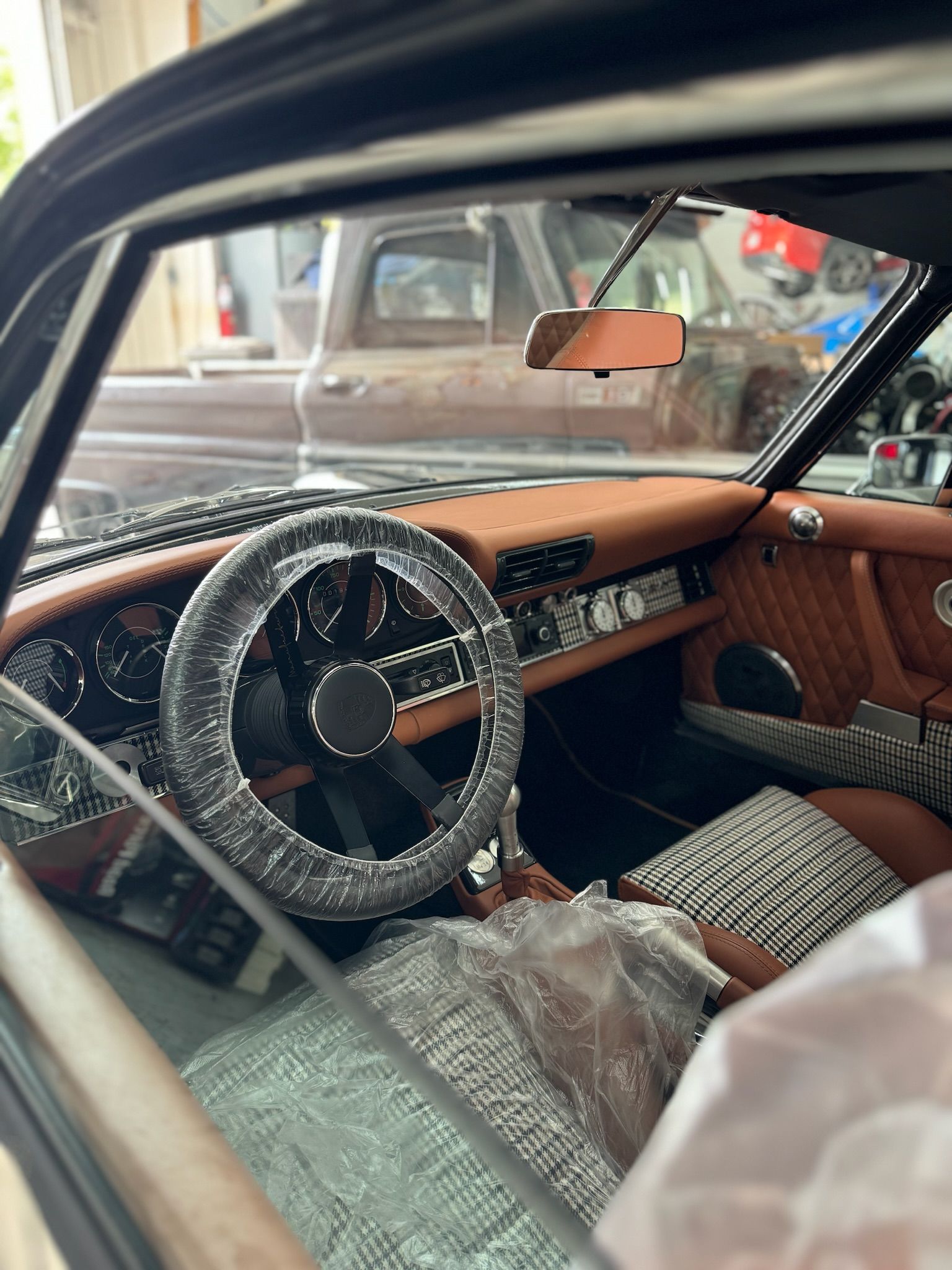 The inside of a car with a steering wheel wrapped in plastic.