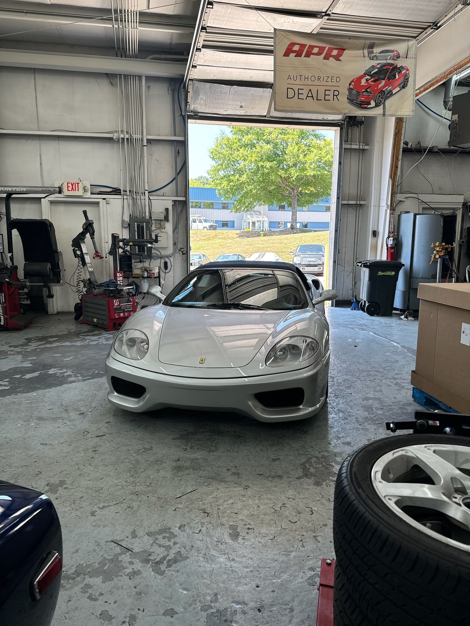 A silver sports car is parked in a garage with the door open.