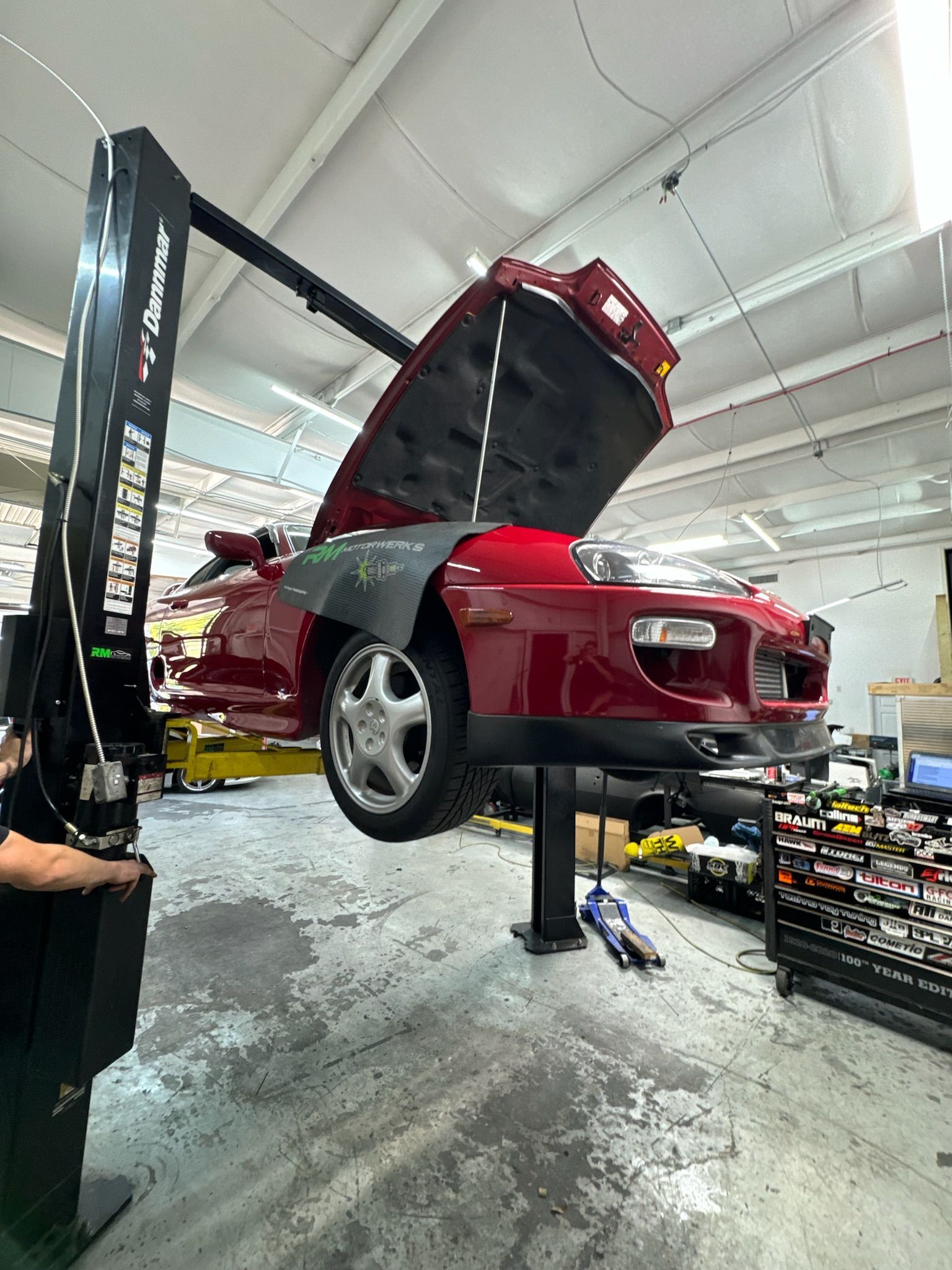 A red car is sitting on top of a lift in a garage.