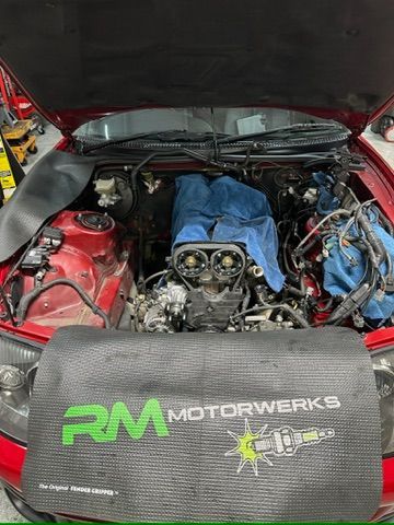 The engine of a red car is being worked on.