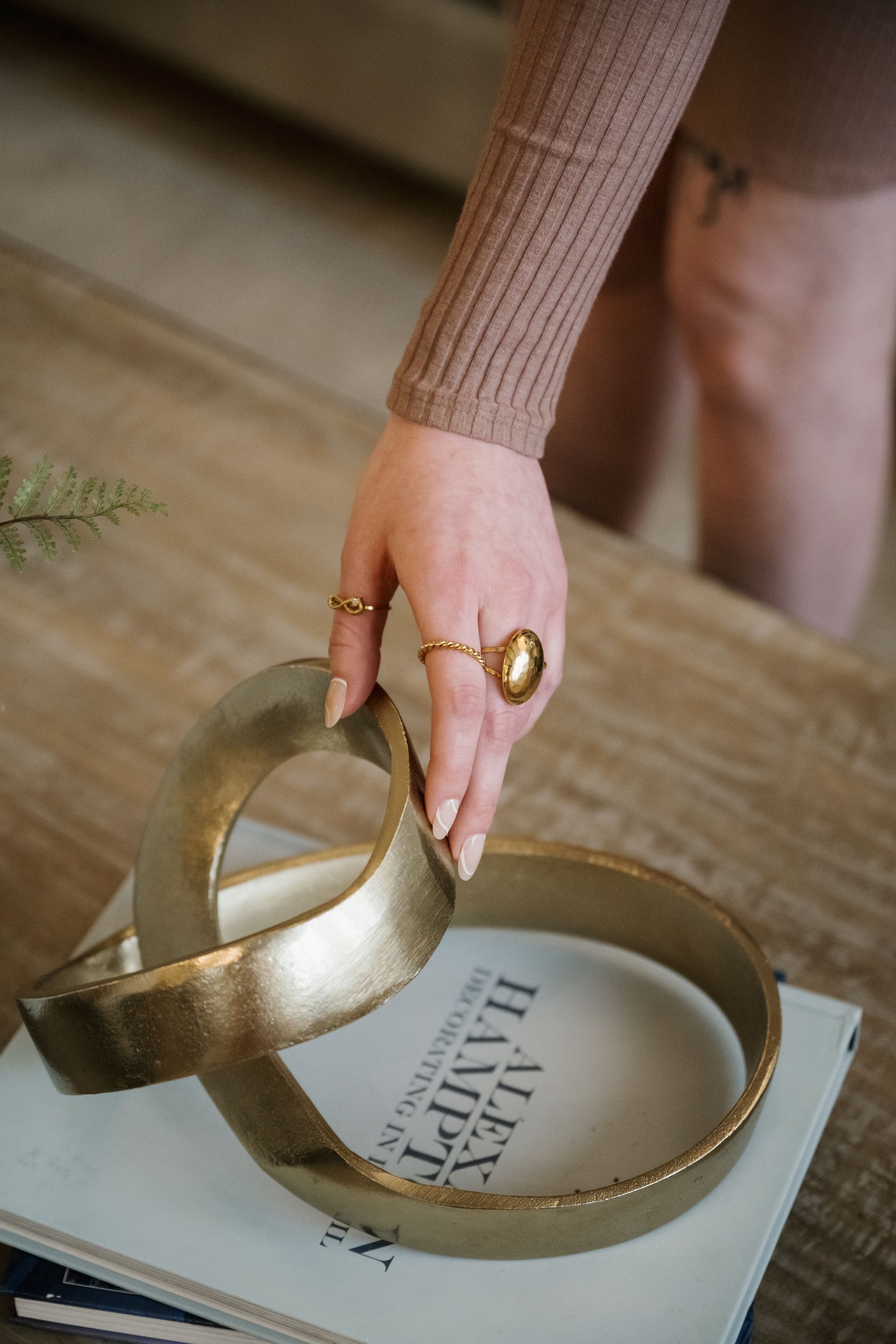 Hand placing a gold metallic bowl on a wooden floor beside another matching bowl