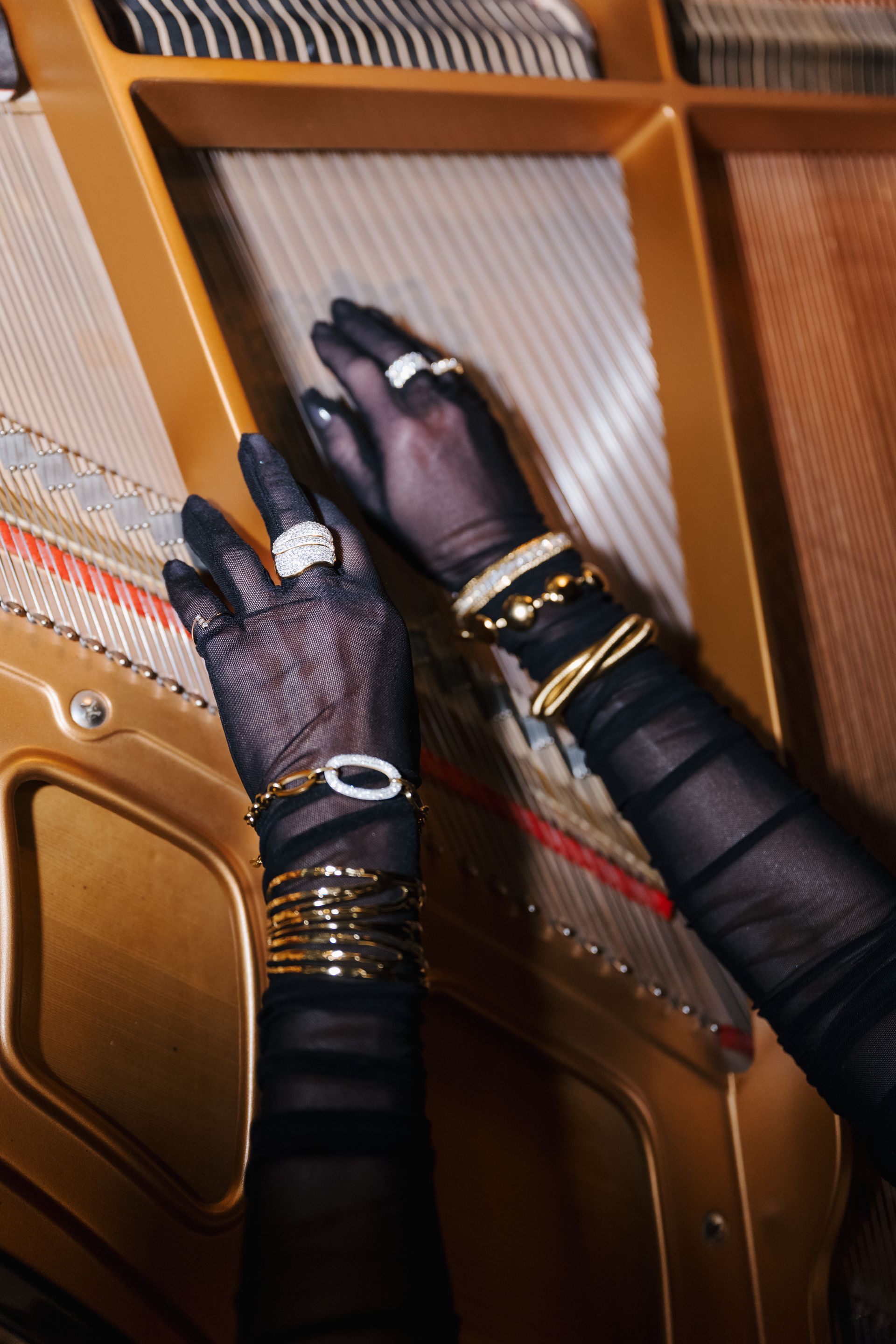 Gloved hands adjusting strings inside a wooden piano frame