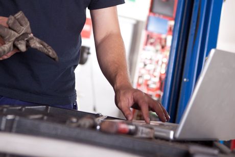 A man is working on a laptop in a garage