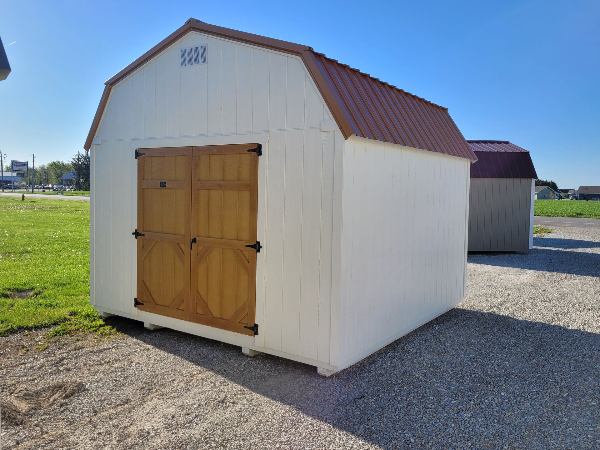 White shed with brown double doors and a brown roof, outdoors.