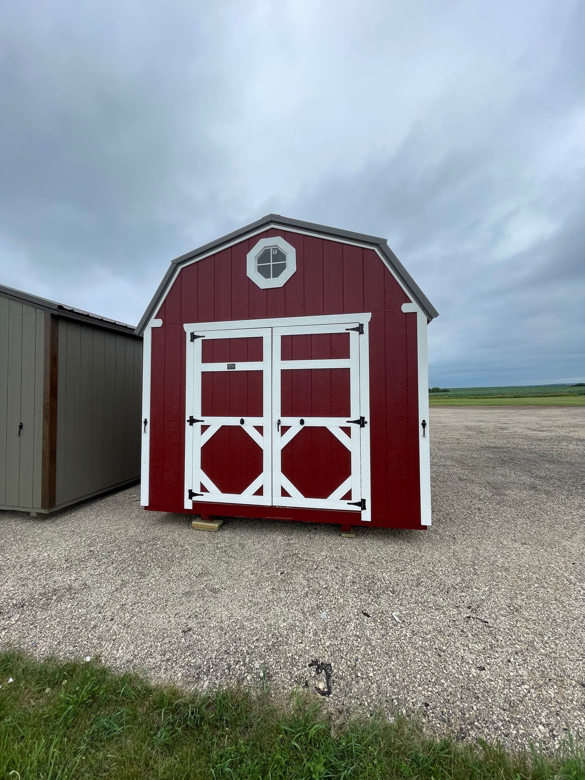 Red and white shed with double doors, octagonal accents, and a small window.