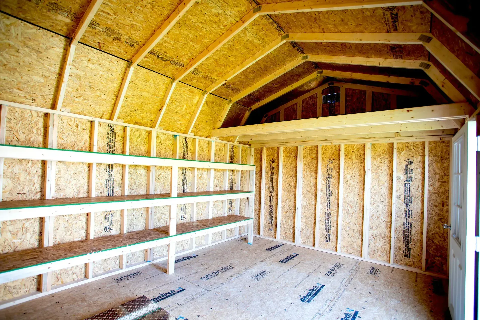 Interior of a wooden shed with shelving along one wall and a loft area.