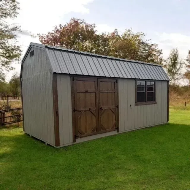 Tan shed with a metal roof, brown doors and trim, and a small window on a grassy lawn.