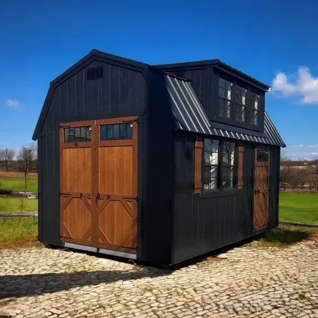 Black barn-style shed with wooden doors and trim, small upper level with windows; sunny outdoor setting.