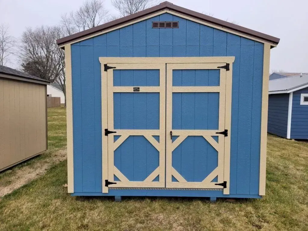 Blue shed with tan door frame and brown roof trim; outdoors.