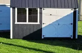 Black and white shed with a window and double doors on a grassy lawn.