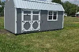 Gray shed with white trim, metal roof, and double doors, set in a grassy yard.