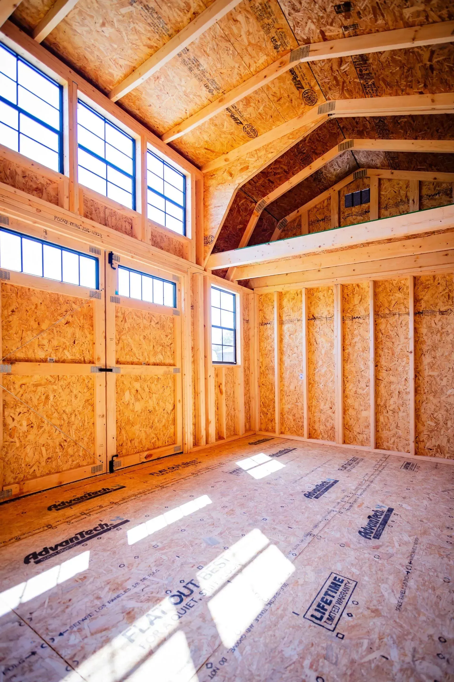 Interior of a wood-framed building under construction with natural light streaming through windows.
