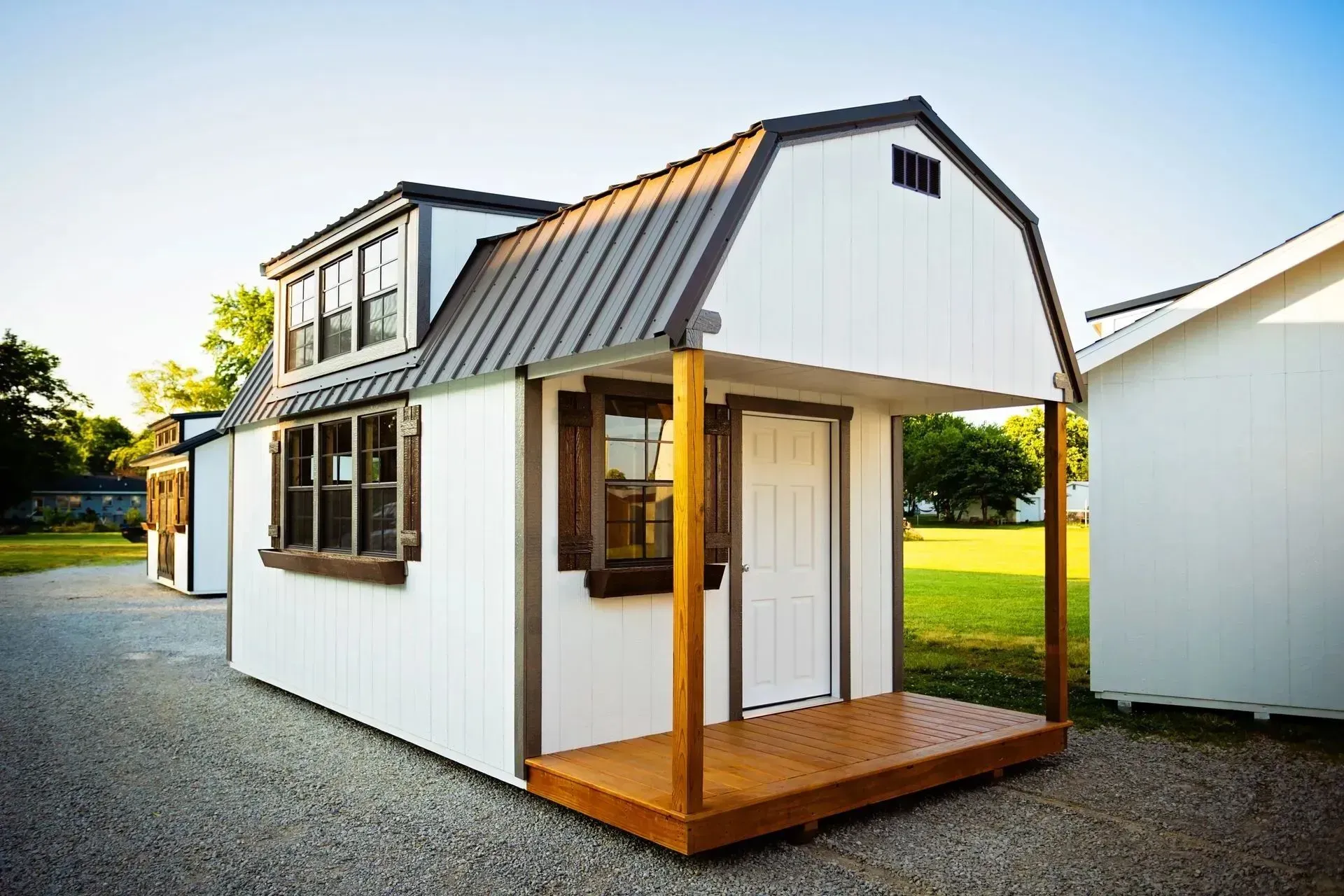White tiny house with a brown porch and metal roof, sunny day.