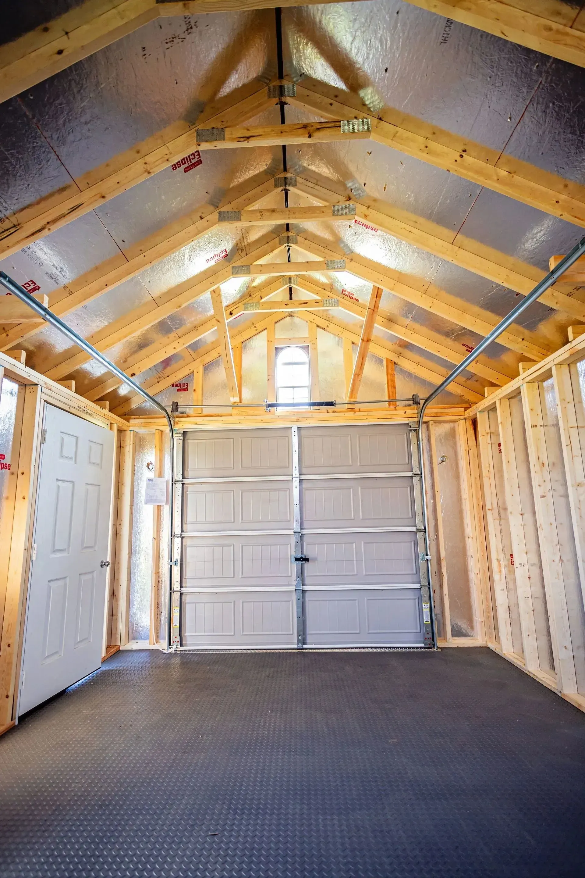 Interior of a garage with a closed door, overhead door, and wooden frame.