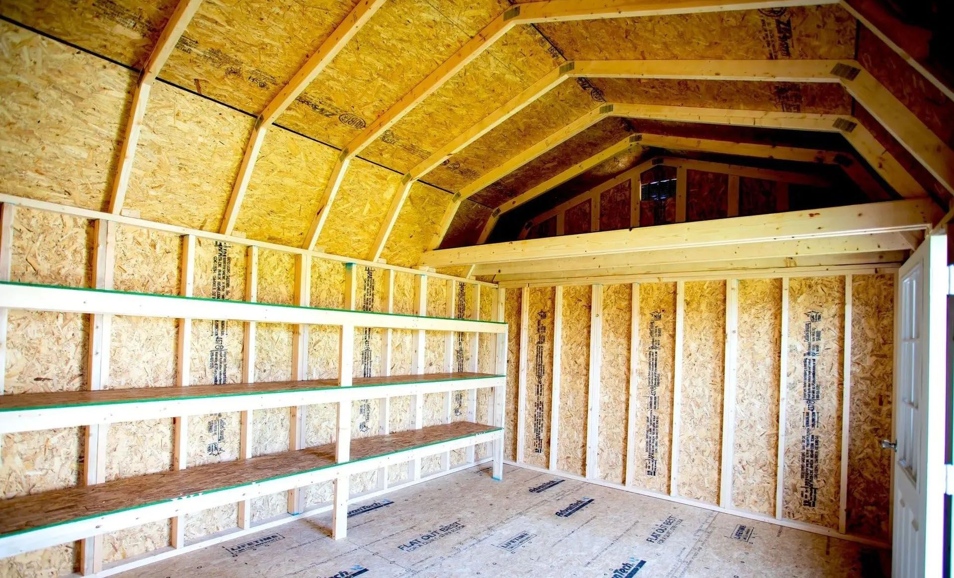 Interior view of a wooden shed with shelving along one wall and a loft area.