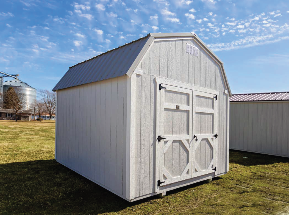 White wooden barn-style shed with double doors and metal roof on grassy field.