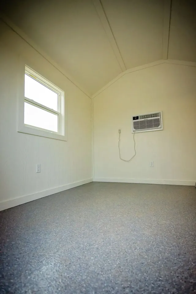 Empty interior room with a window, air conditioner, and gray floor.