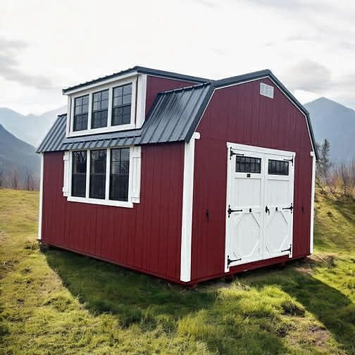 A red and white barn-style shed with a dormer and black metal roof, situated in a mountain landscape.