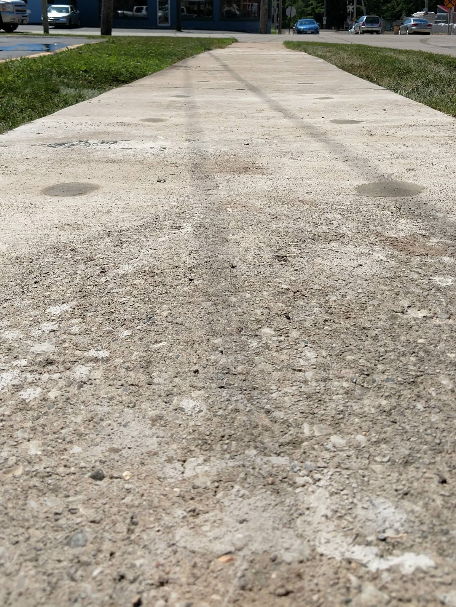 concrete sidewalk with grass on the side of it - after