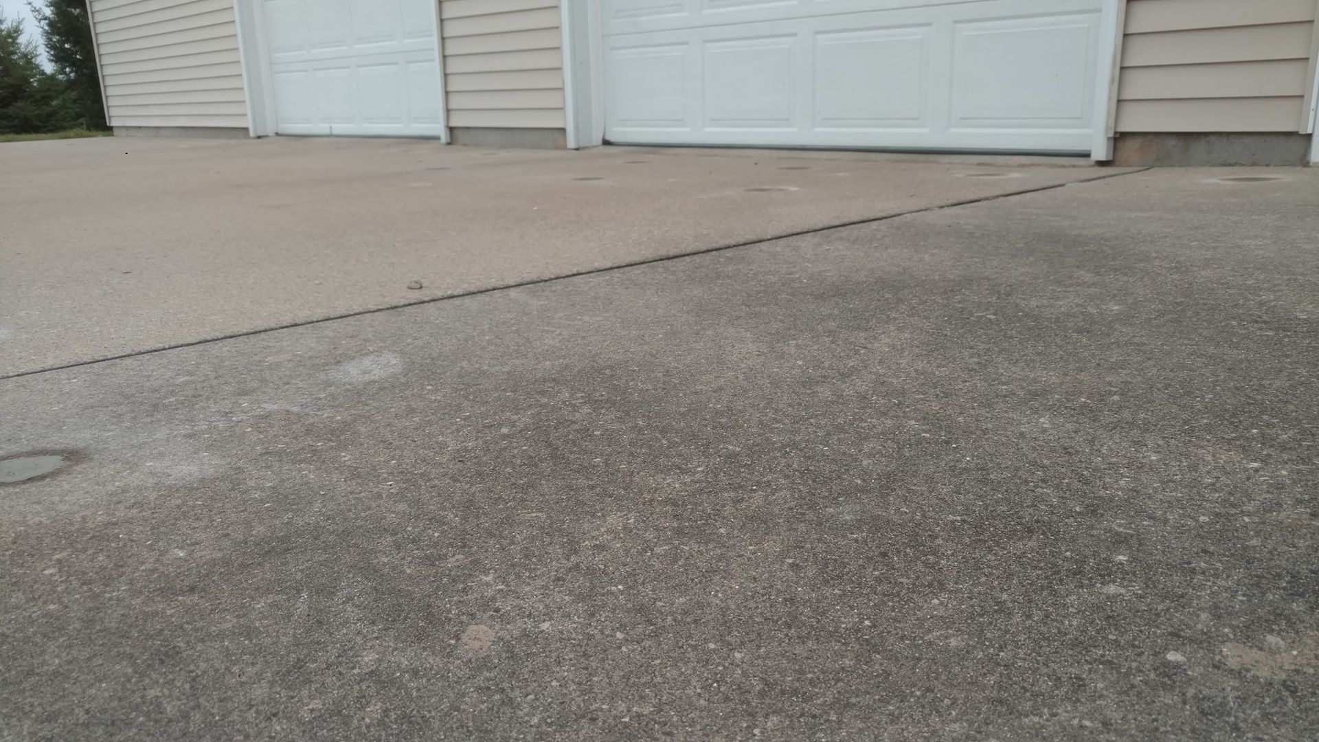 A concrete driveway with a white garage door in the background - after