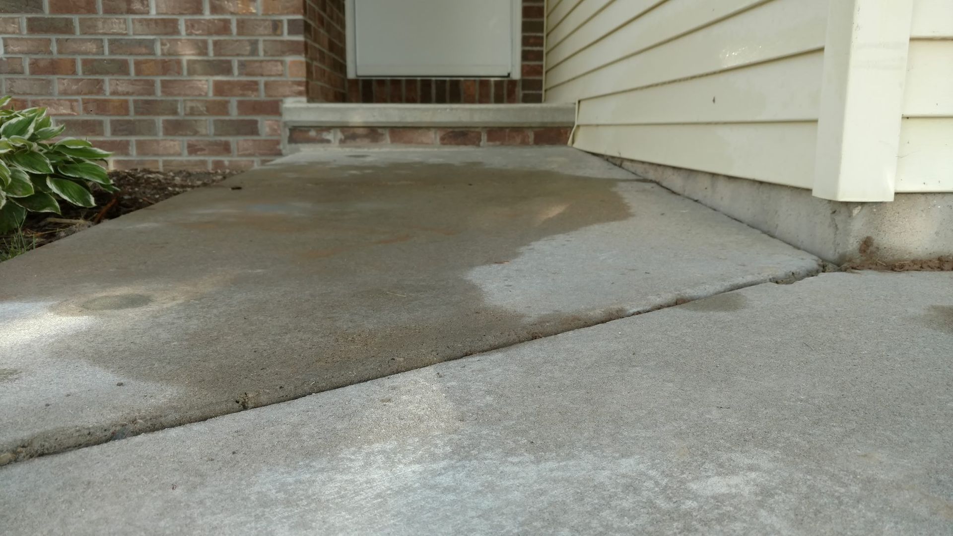 A concrete walkway leading to the front door of a house - after