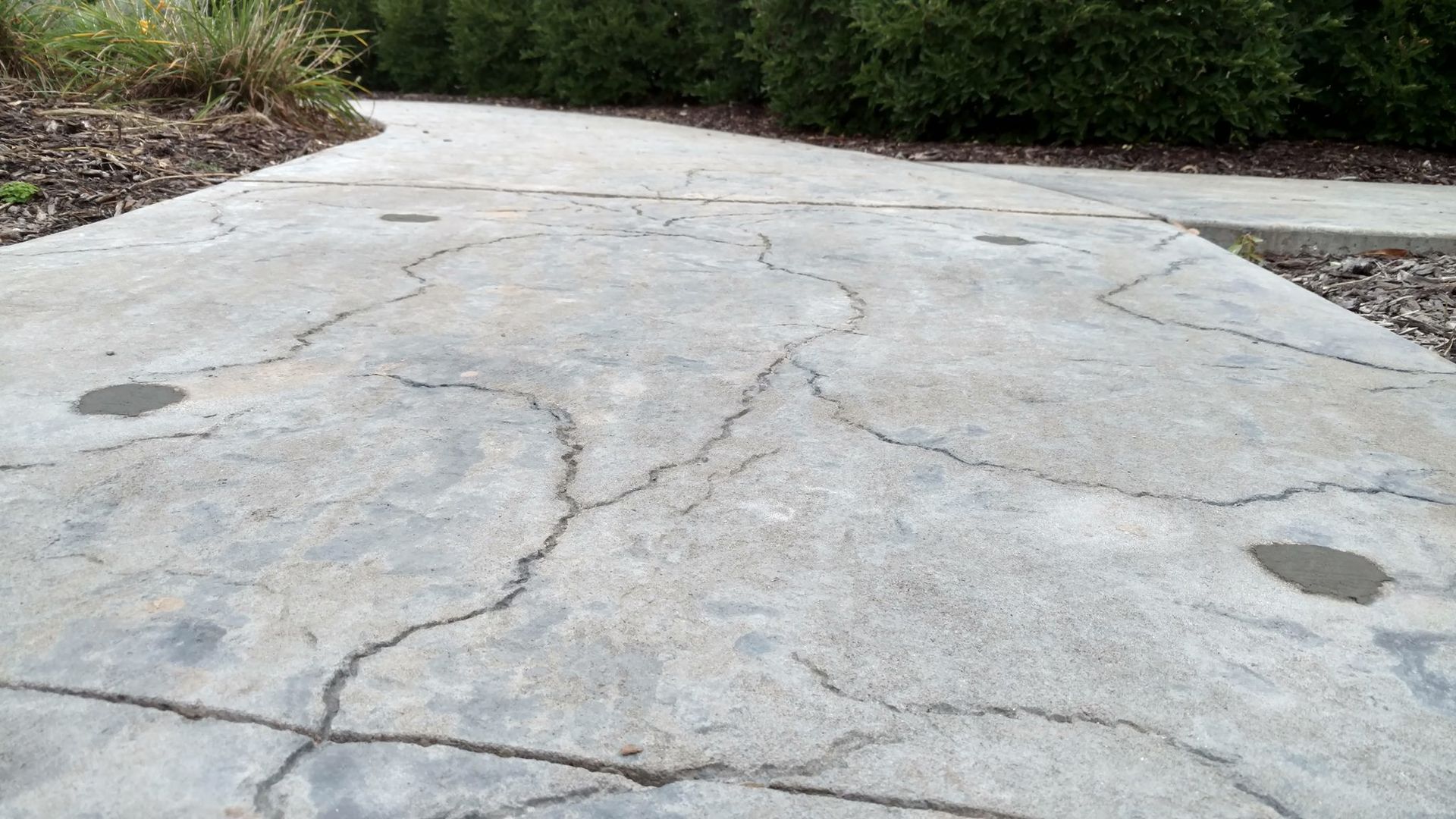 A cracked concrete walkway with a yellow stripe on the side - after