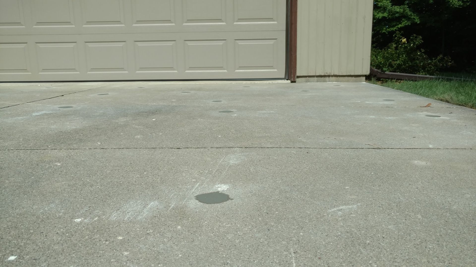 A concrete driveway with a garage door in the background - after