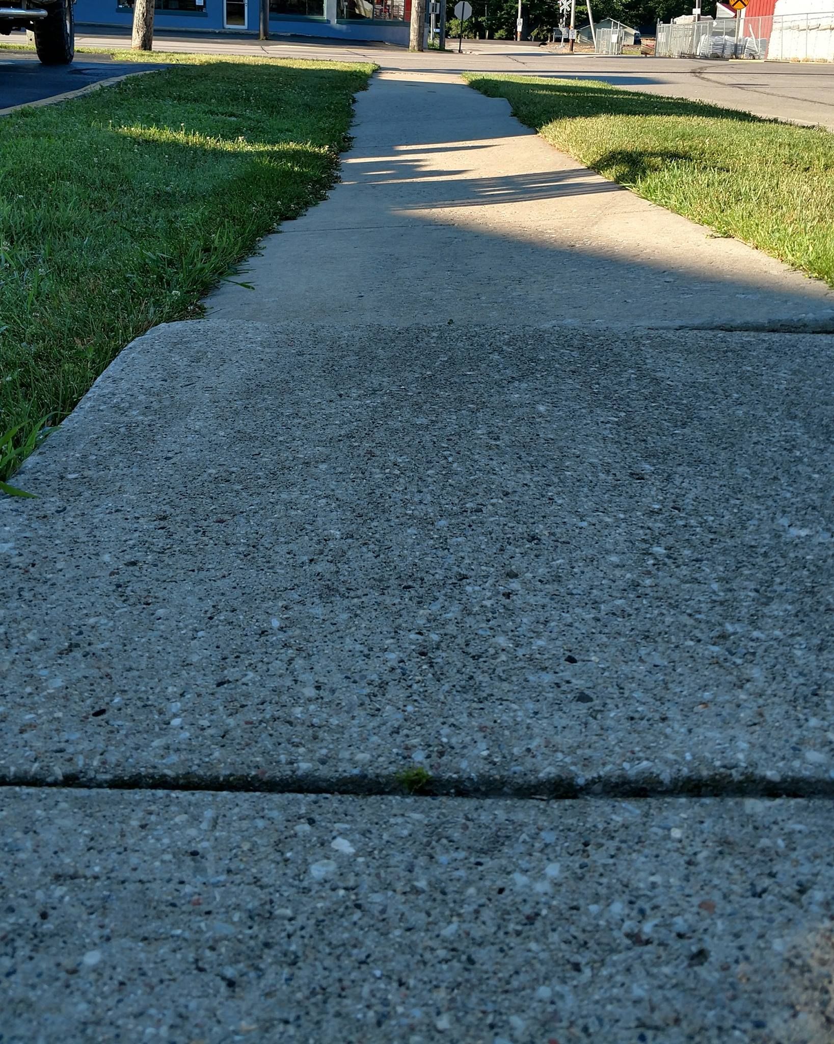 concrete sidewalk with grass on the side of it - before