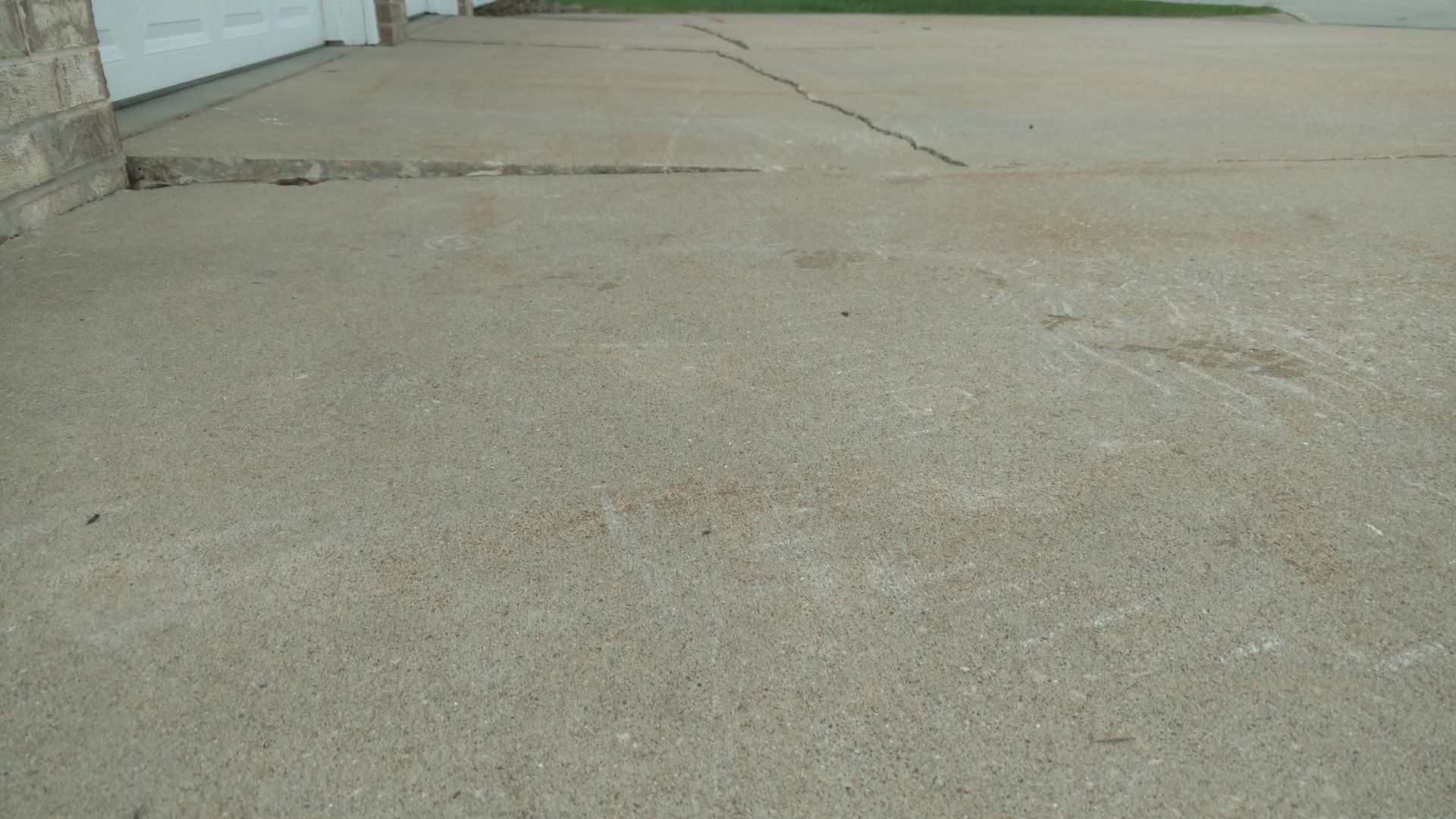 A concrete driveway with a white garage door in the background - before