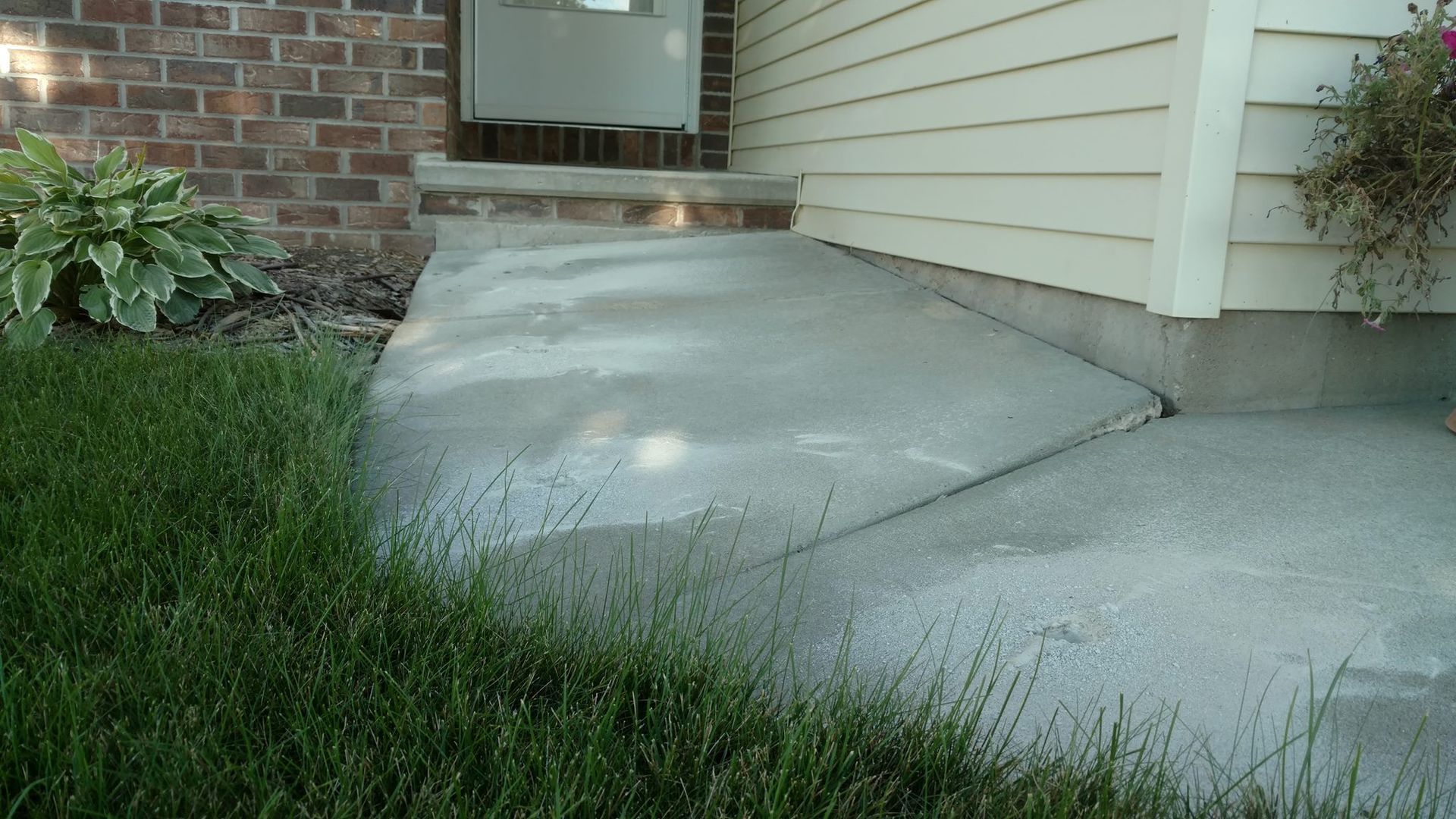 A concrete walkway leading to the front door of a house - before