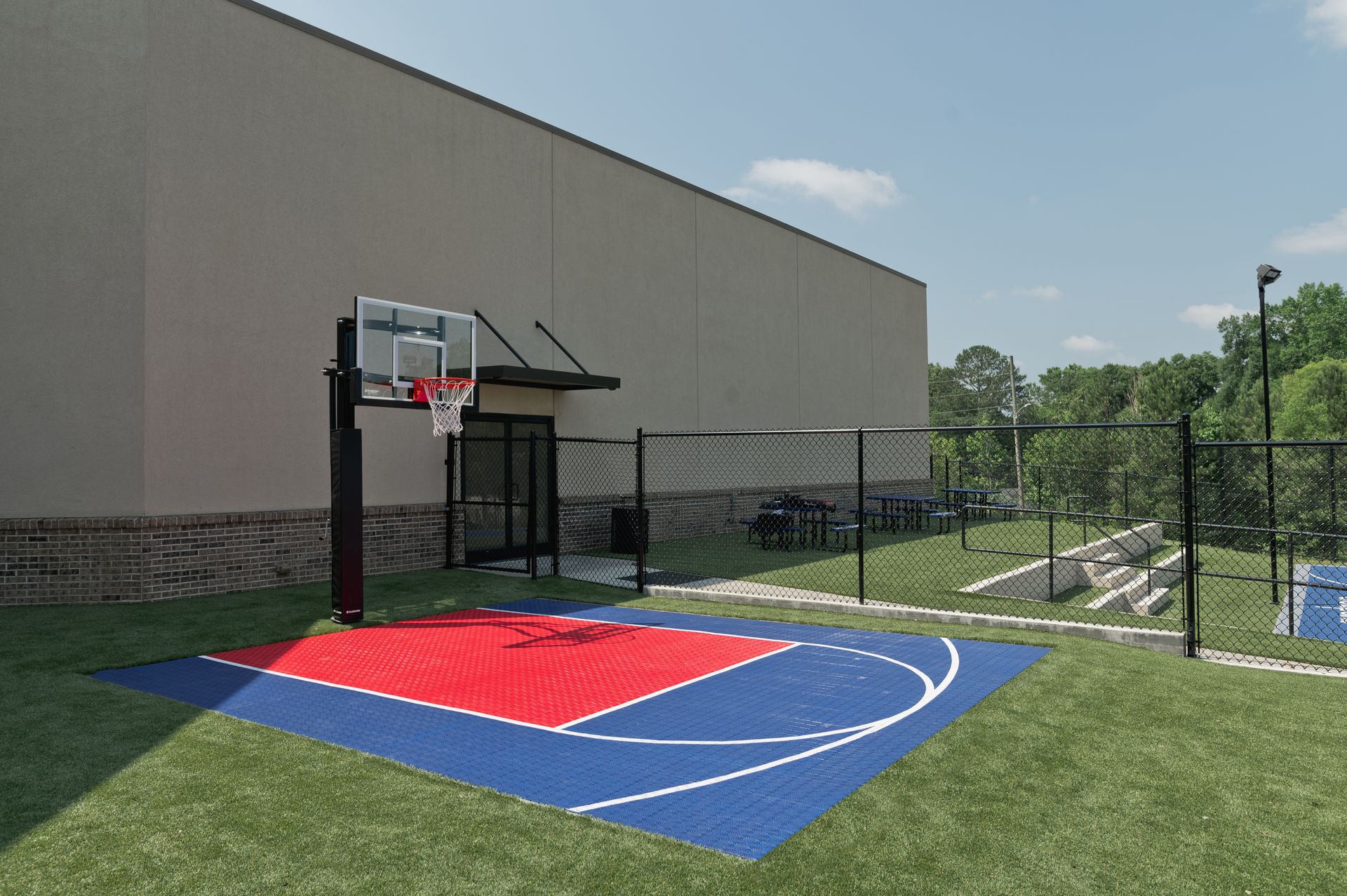 A basketball court in front of a building with a fence around it.