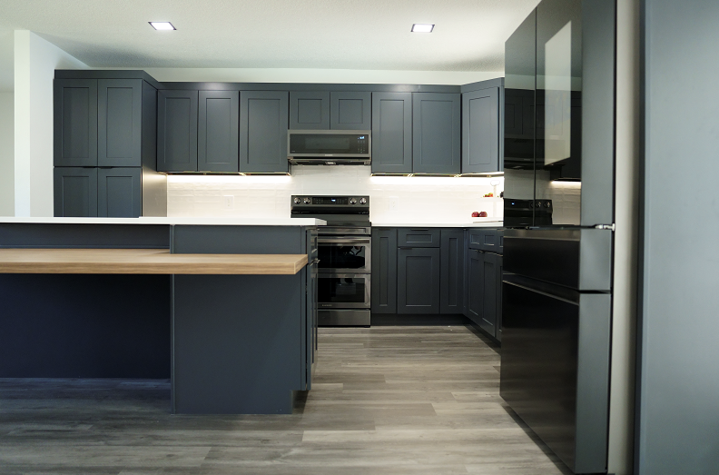 A kitchen with black cabinets and stainless steel appliances