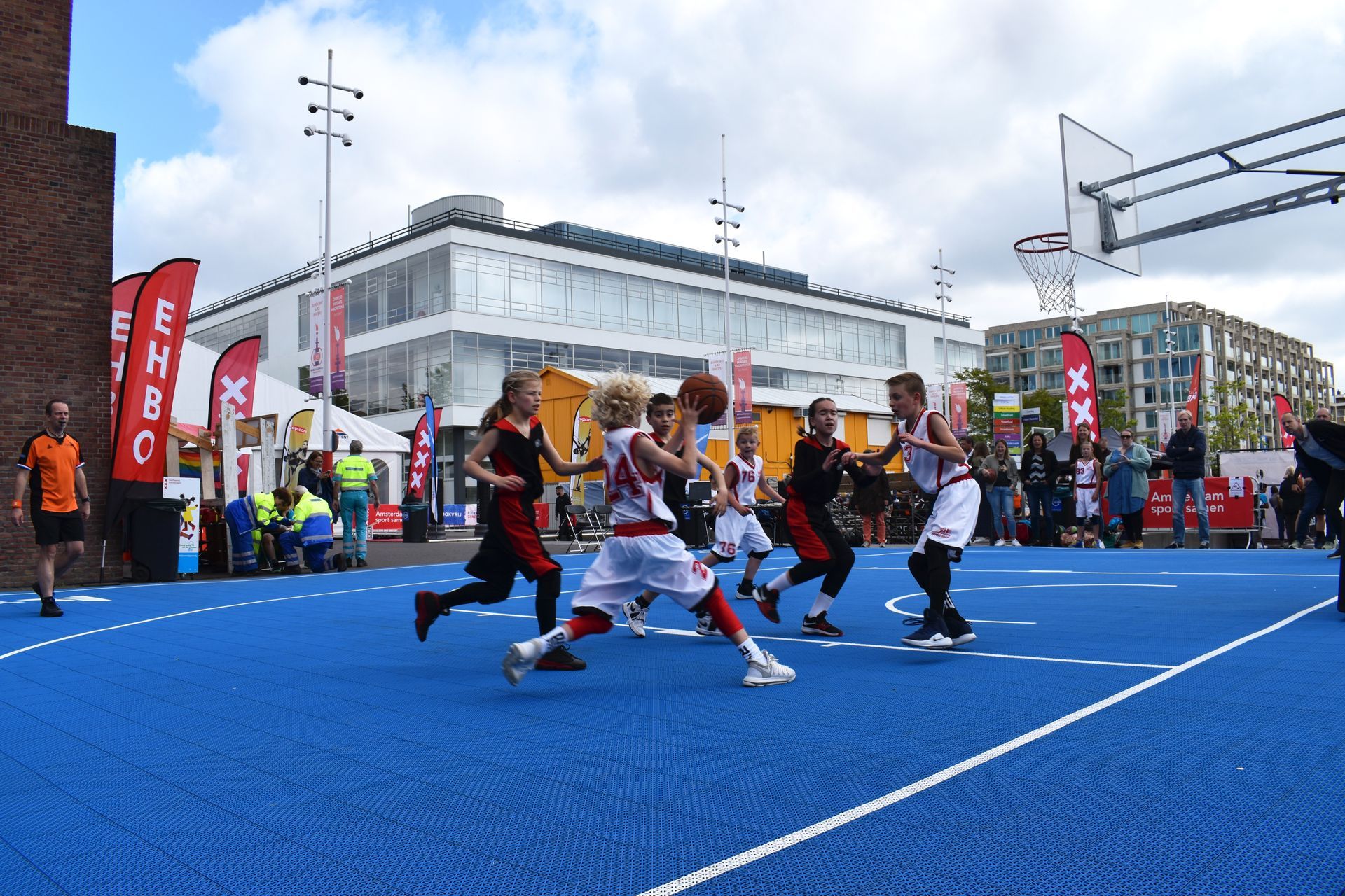A group of young boys are playing basketball on a blue court.